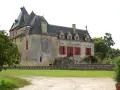 Le **château Olivier**, une bâtisse de pierre aux volets rouges, se dresse fièrement entouré de verdure.