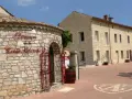 Bienvenue au **domaine de la Croix Blanche**. Une bâtisse en pierre avec une enseigne élégante et une porte ornée de ferronneries rouges.
