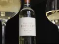 Bouteille de vin blanc Château Bouscaut Pessac-Léognan entre deux verres de vin.