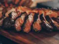 Tranches de viande grillée sur une planche en bois. Idéal pour savoir que boire avec une pierrade viande.