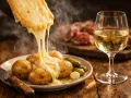 Raclette fondant sur des pommes de terre, avec cornichons et un verre de vin blanc pétillant. Parfait pour savoir quel est le meilleur crémant.