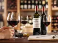 Dégustation de ce meilleur vin rouge bordeaux, avec des verres remplis et des bouteilles sur une table en bois, dans une cave à vin.
