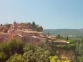 Village perché aux toits de tuiles roses, entouré de verdure. Au loin, des collines rappellent les vignes oubliées d'une Provence intemporelle.