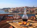 Verre de porto tawny ou ruby, deux verres à vin et des pâtisseries sur une table en bois, avec la ville de Porto en arrière-plan.