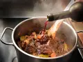 Un vin rouge est versé dans un plat mijoté de bœuf, carottes et herbes. Quel vin bourguignon sublimera ce plat ?