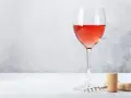 Un verre de bon rosé, prêt à être dégusté, avec un tire-bouchon et un bouchon à proximité.