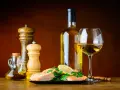 Un plat de saumon avec citron et persil, accompagné d'une bouteille et d'un verre de vin blanc, moulin à poivre et salière, huile d'olive. Le meilleur vin blanc pour cuisiner est prêt.