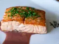 Un filet de saumon cuit, garni de ciboulette, baignant dans une sauce rouge. Un délice qui invite à se demander quel vin rouge avec du saumon cuit serait parfait.