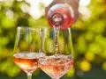 Un verre de rosé est servi dans un autre verre, sous un soleil radieux. Un moment parfait pour boire du rosé tous les jours.
