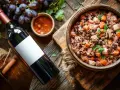 Un plat de céréales et légumes, accompagné d'une sauce, de raisins et d'une bouteille de vin rouge.