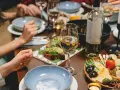 Un dîner convivial avec des amis, des assiettes garnies, des bougies et une bouteille de vin pour cuisiner et accompagner le repas.