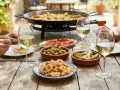 Un repas ensoleillé avec une paella fumante, des calamars frits, des olives, des cœurs d'artichauts, des tomates et un verre de vin blanc.