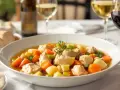 Un plat de poule au pot réconfortant, servi avec du pain et un verre de vin.