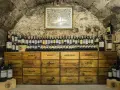 Cave à vin de la côte de Beaune, remplie de bouteilles et de caisses en bois étiquetées avec des noms de villes.
