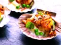 Saint-jacques poêlées, tendres et dorées, servies dans leur coquille avec des petits pois et une touche de vin rouge.