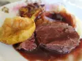 Tranches de chevreuil en sauce avec purée et pomme rôtie.