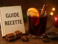 Un verre de vin chaud aux épices, prêt à réchauffer 50 personnes. Un livre "Guide Recette" à côté.