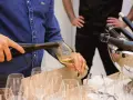 Un homme verse du vin blanc, peut-être un pinot gris, dans un verre. Il sera parfait avec du poisson.