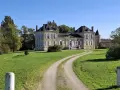 Un magnifique chateau la France, avec une allée sinueuse traversant une pelouse verdoyante sous un ciel bleu clair.