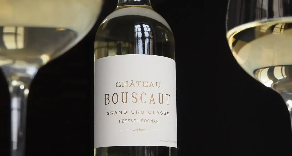 Bouteille de vin blanc Château Bouscaut Pessac-Léognan entre deux verres de vin.