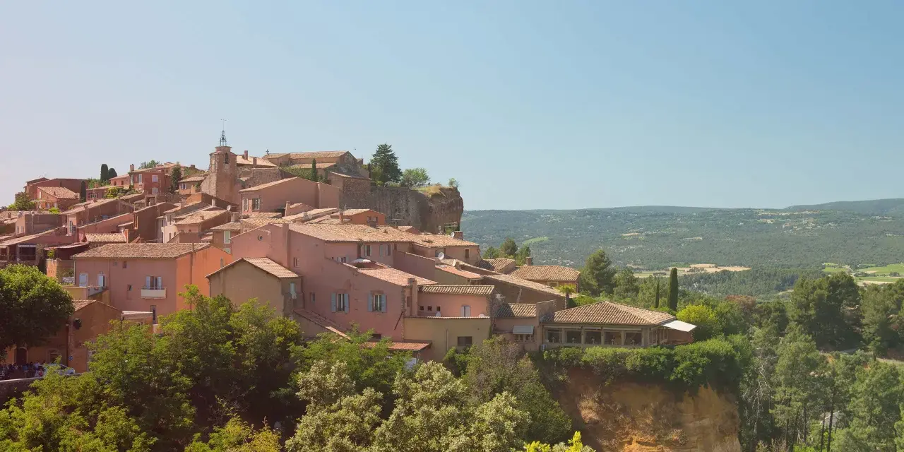 Village perché aux toits de tuiles roses, entouré de verdure. Au loin, des collines rappellent les vignes oubliées d'une Provence intemporelle.