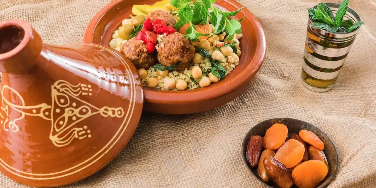 Un plat de couscous aux boulettes de viande, garni de menthe fraîche, accompagné d'un verre de thé à la menthe et de fruits secs. Un délice pour accompagner un bon vin.