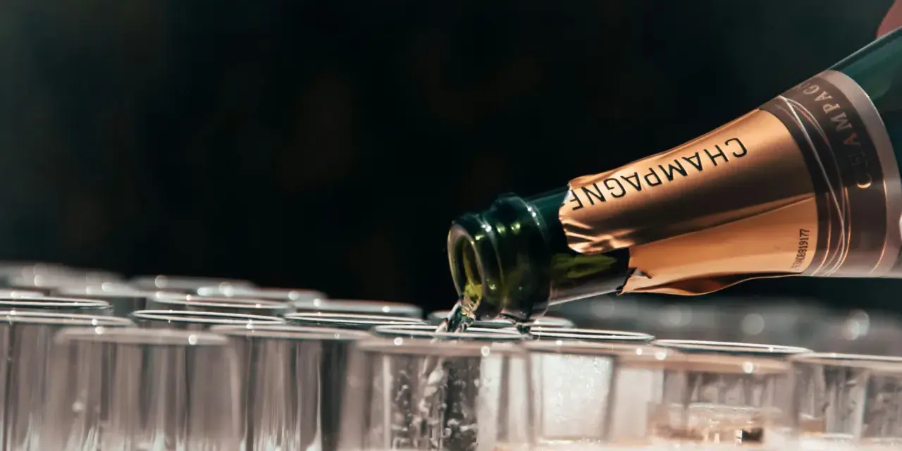 Une bouteille de champagne verse son contenu pétillant dans une rangée de flûtes. Le début d'une célébration avec le meilleur champagne du monde.