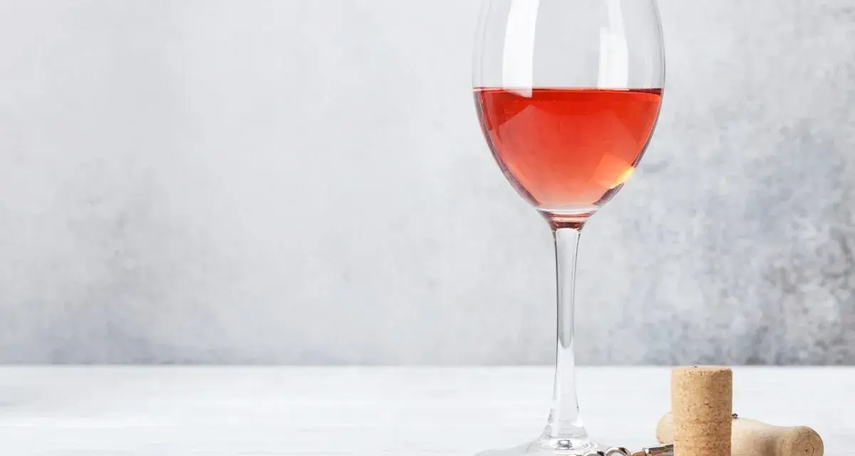 Un verre de bon rosé, prêt à être dégusté, avec un tire-bouchon et un bouchon à proximité.