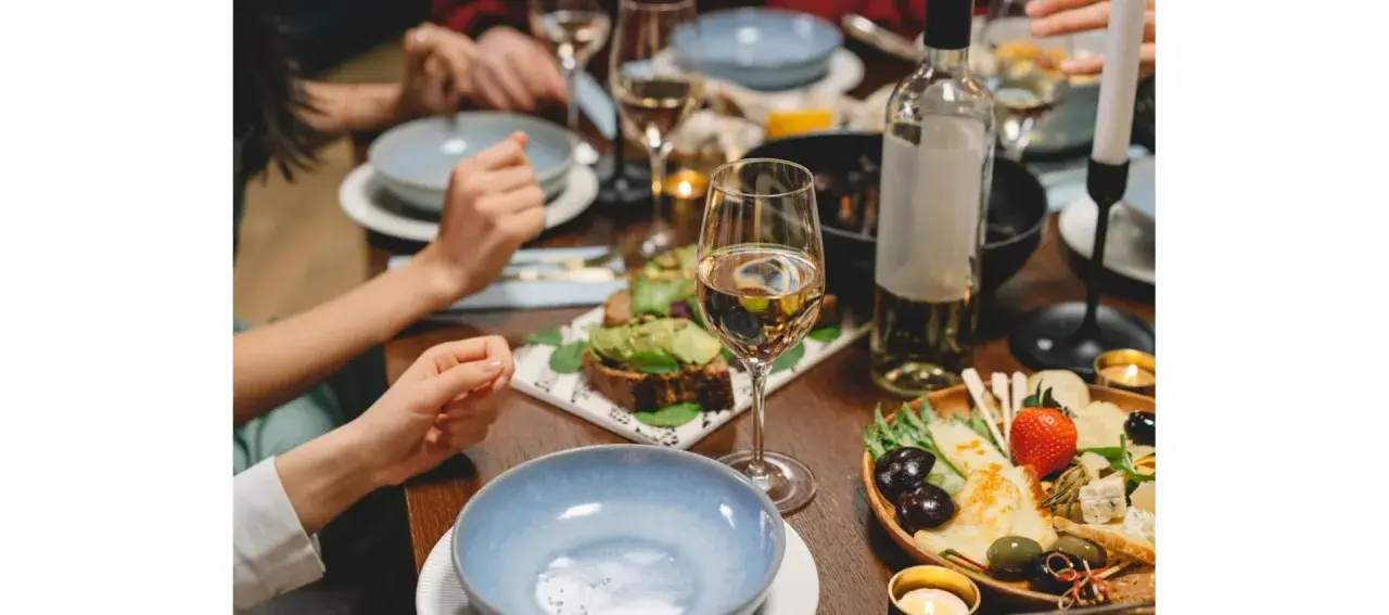 Un dîner convivial avec des amis, des assiettes garnies, des bougies et une bouteille de vin pour cuisiner et accompagner le repas.