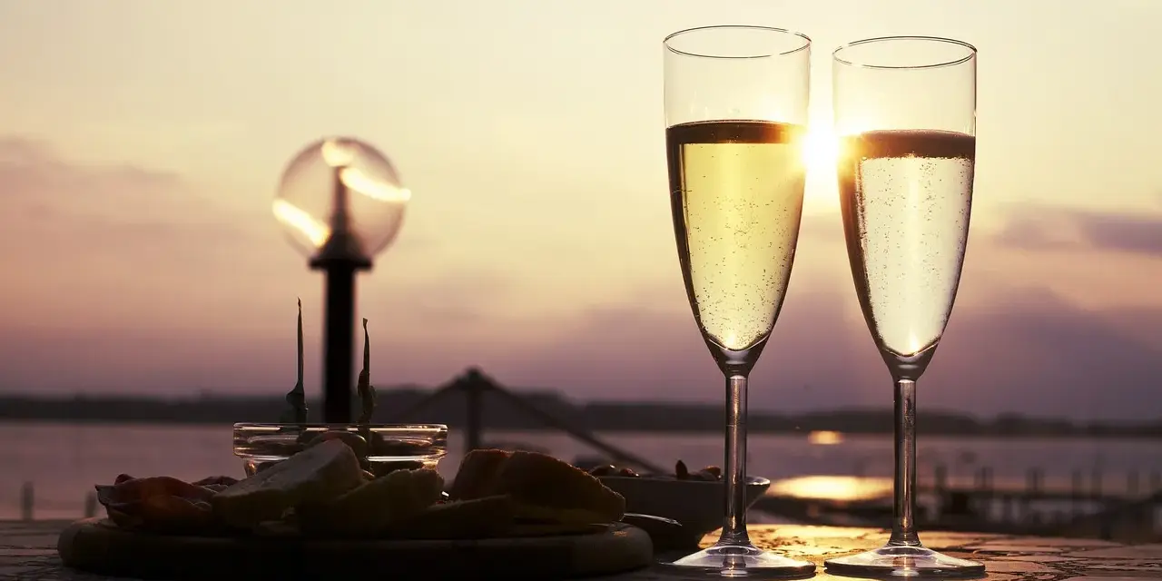 Deux flûtes de le meilleur prosecco scintillent au soleil couchant, accompagnées d'une assiette d'amuse-bouches.