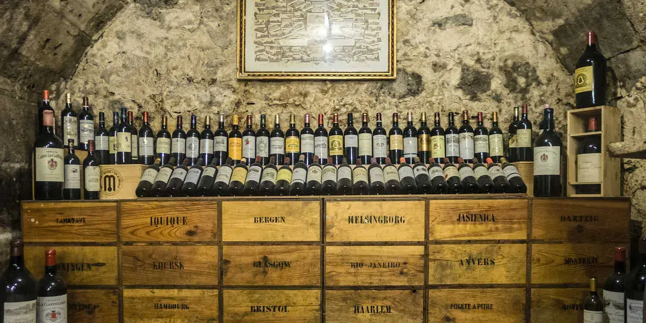 Cave à vin de la côte de Beaune, remplie de bouteilles et de caisses en bois étiquetées avec des noms de villes.