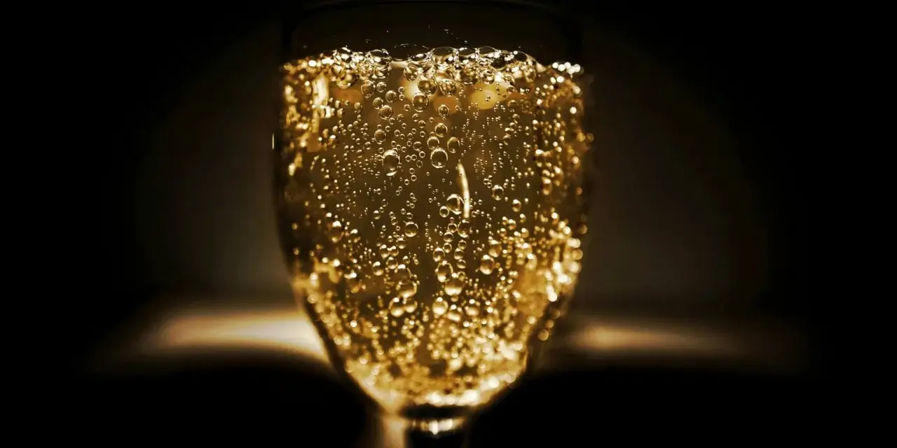 Un verre de vin mousseux scintillant, rempli de bulles dorées, prêt à célébrer.