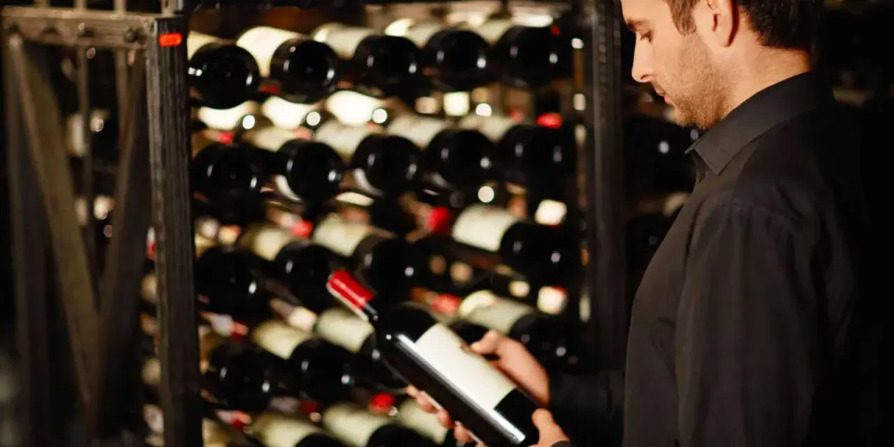 Un homme examine une bouteille de vin dans une cave. Une belle opportunité d'investir dans le vin.