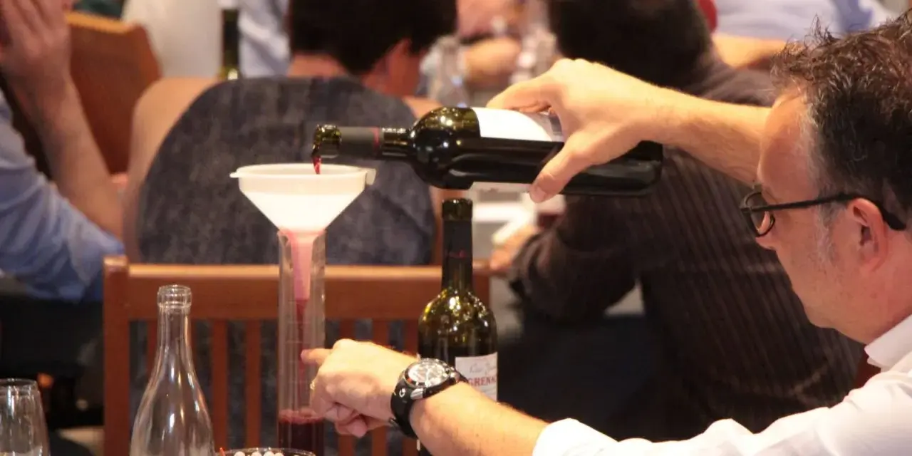 Dégustation de vin rouge, un homme verse du cépage Syrah, d'origine française, dans un verre gradué.