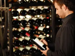 Un homme examine une bouteille de vin dans une cave. Une belle opportunité d'investir dans le vin.