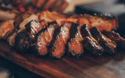 Tranches de viande grillée sur une planche en bois. Idéal pour savoir que boire avec une pierrade viande.