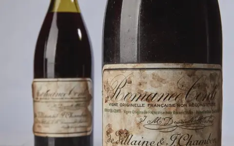 Deux bouteilles de vin Romanée-Conti, dont une avec une étiquette ancienne et jaunie.