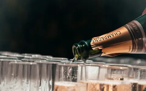 Une bouteille de champagne verse son contenu pétillant dans une rangée de flûtes. Le début d'une célébration avec le meilleur champagne du monde.