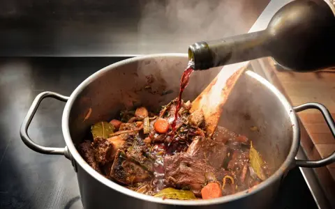 Un vin rouge est versé dans un plat mijoté de bœuf, carottes et herbes. Quel vin bourguignon sublimera ce plat ?