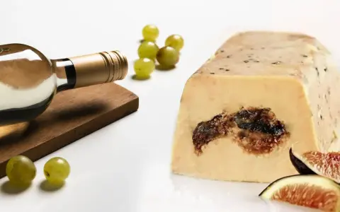 Une bouteille de vin blanc, des raisins et des figues accompagnent ce foie gras. La question est : que boire avec du foie gras ?