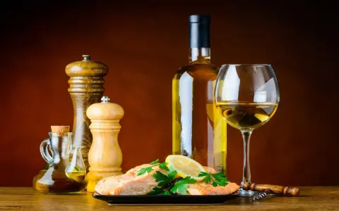 Un plat de saumon avec citron et persil, accompagné d'une bouteille et d'un verre de vin blanc, moulin à poivre et salière, huile d'olive. Le meilleur vin blanc pour cuisiner est prêt.