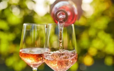Un verre de rosé est servi dans un autre verre, sous un soleil radieux. Un moment parfait pour boire du rosé tous les jours.