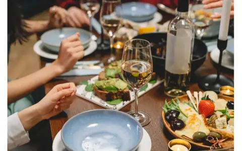Un dîner convivial avec des amis, des assiettes garnies, des bougies et une bouteille de vin pour cuisiner et accompagner le repas.