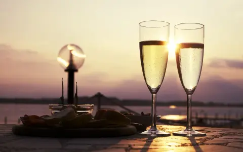 Deux flûtes de le meilleur prosecco scintillent au soleil couchant, accompagnées d'une assiette d'amuse-bouches.