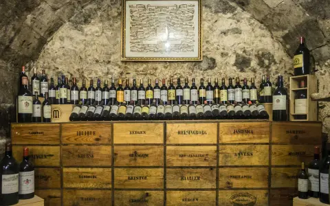 Cave à vin de la côte de Beaune, remplie de bouteilles et de caisses en bois étiquetées avec des noms de villes.