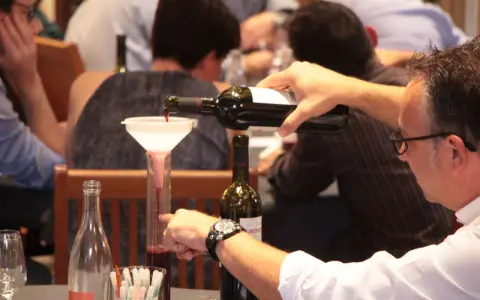 Dégustation de vin rouge, un homme verse du cépage Syrah, d'origine française, dans un verre gradué.