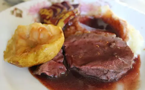 Tranches de chevreuil en sauce avec purée et pomme rôtie.