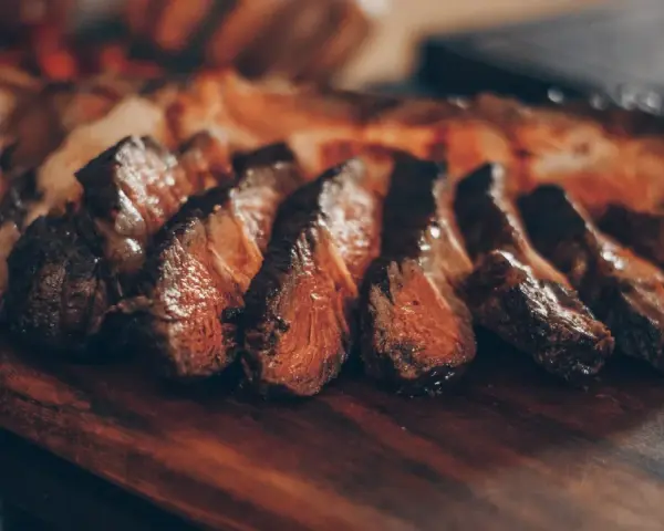 Tranches de viande grillée sur une planche en bois. Idéal pour savoir que boire avec une pierrade viande.