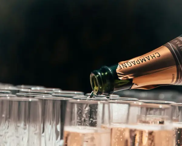 Une bouteille de champagne verse son contenu pétillant dans une rangée de flûtes. Le début d'une célébration avec le meilleur champagne du monde.