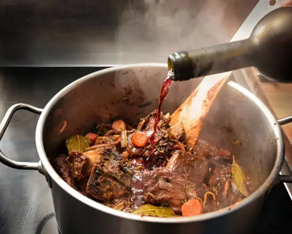 Un vin rouge est versé dans un plat mijoté de bœuf, carottes et herbes. Quel vin bourguignon sublimera ce plat ?